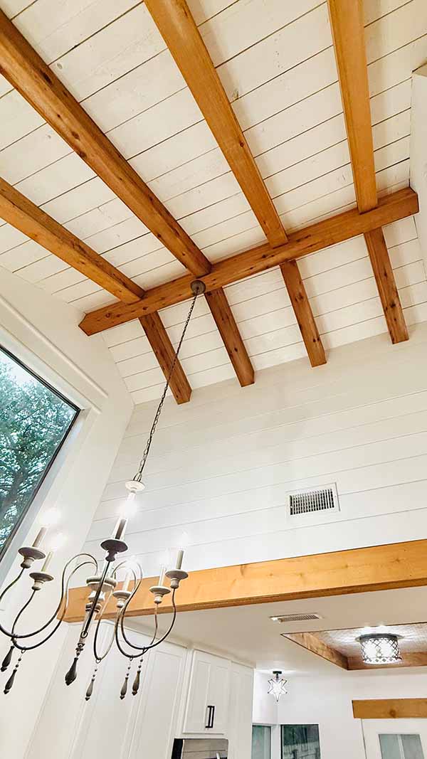 Interior room with vaulted ceiling, exposed wooden beams, and farmhouse chandelier