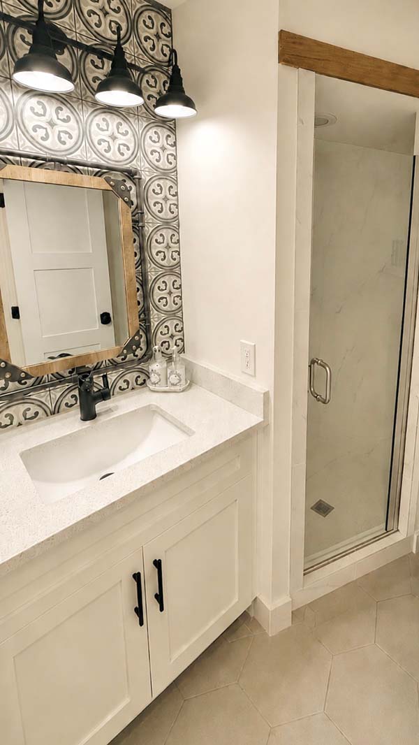 Painted white bathroom vanity with patterned tile backsplash and wood beam accent in North Dallas