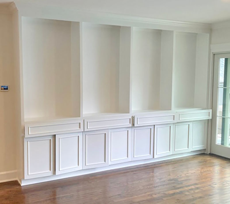 Painted white built-in shelving unit with panel cabinet doors in North Dallas living room
