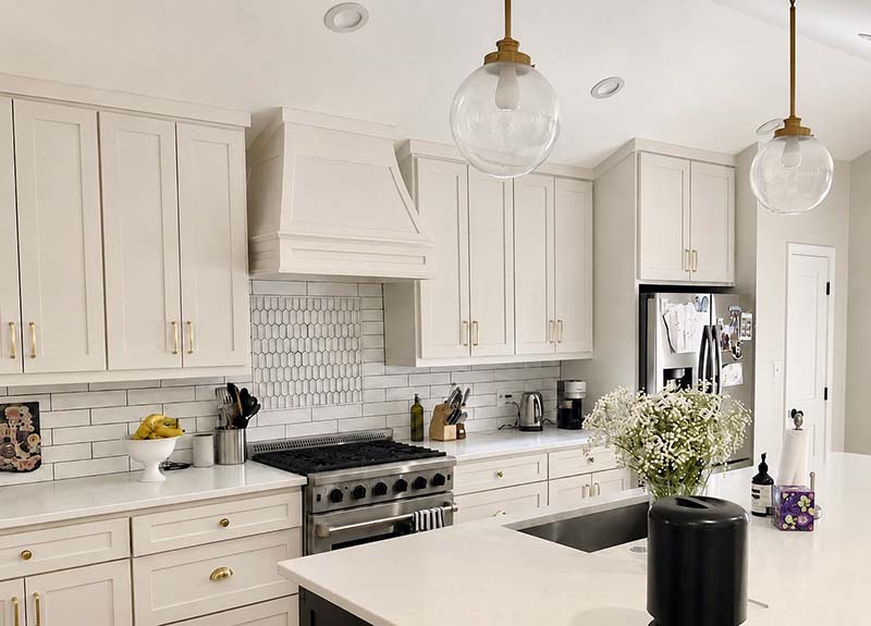 Freshly painted white kitchen cabinets with gold hardware and subway tile backsplash in North Dallas home