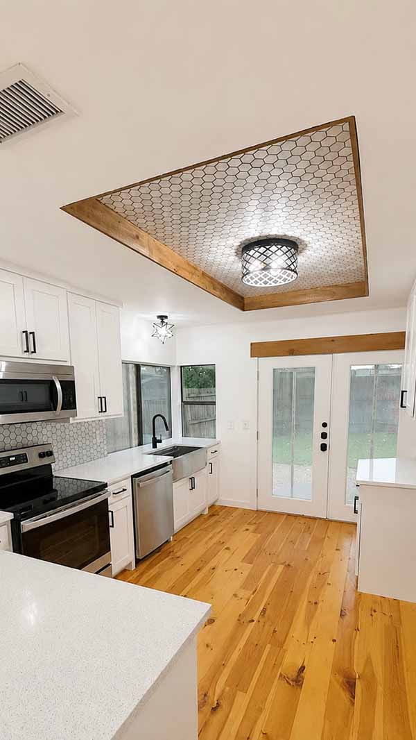 Painted white kitchen cabinets with decorative tray ceiling and hex tile detail in North Dallas home
