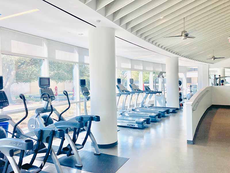 Painted commercial gym with white structural columns, painted ceiling beams, and epoxy floor in North Dallas fitness center