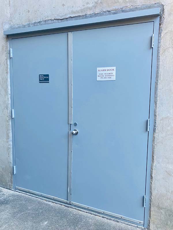Painted gray industrial double doors on exterior concrete wall at North Dallas commercial facility