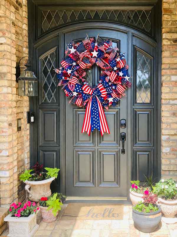 Painted dark gray arched front door with decorative wreath on brick home in North Dallas