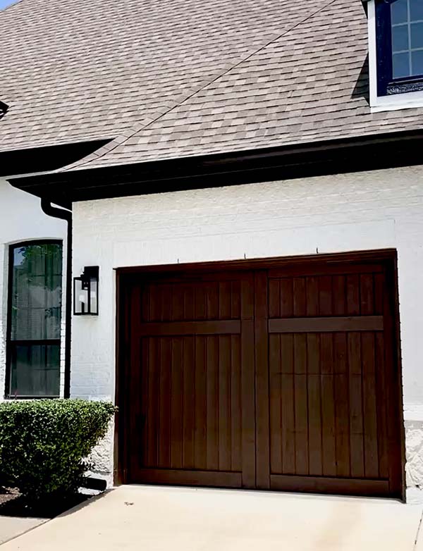 Stained dark wood garage door against painted white brick home in North Dallas
