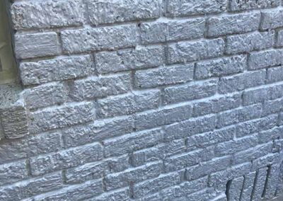 exterior brick wall covered in chemical paint stripper showing thick white gel lifting paint from surface