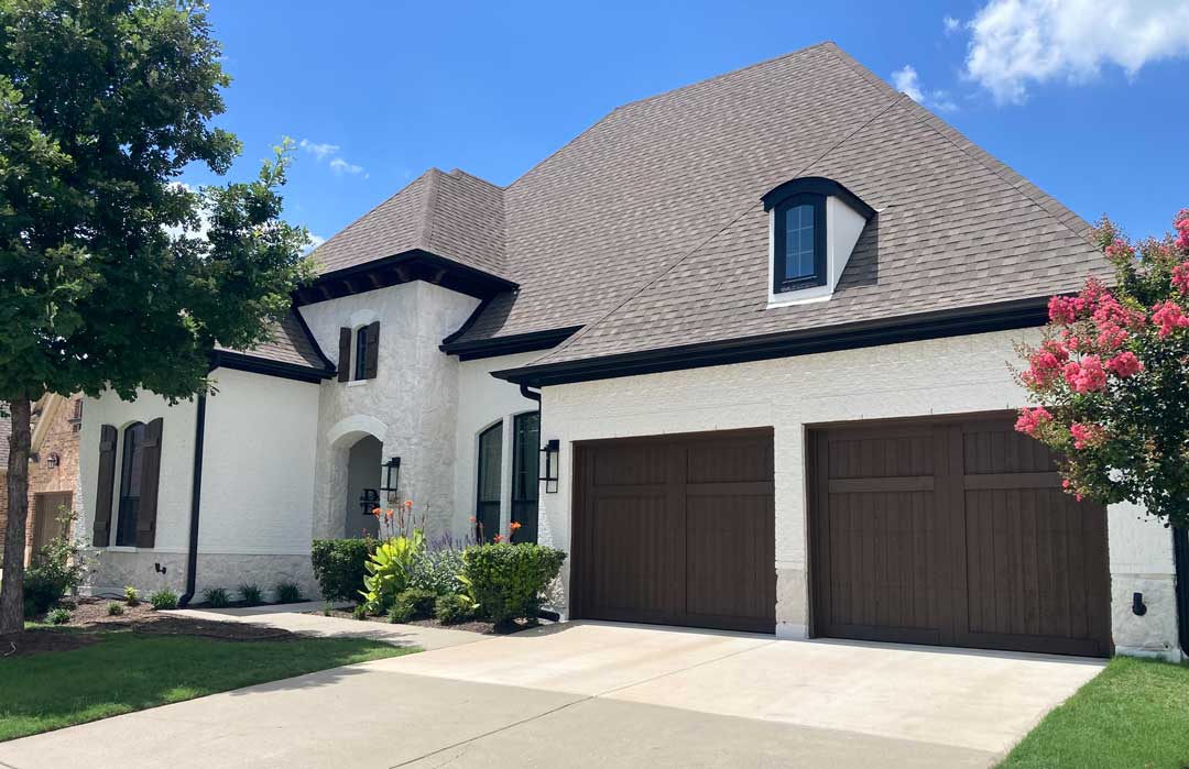 Completed exterior house painting on a two-story home with white painted brick and dark trim accents