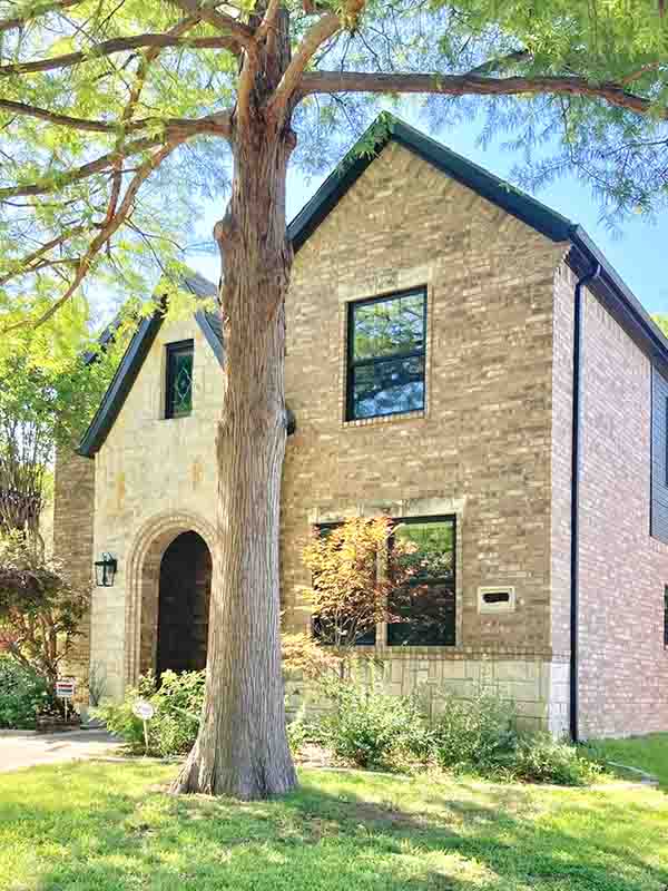 Two-story brick home with painted dark trim, arched entry, and black window frames in North Dallas