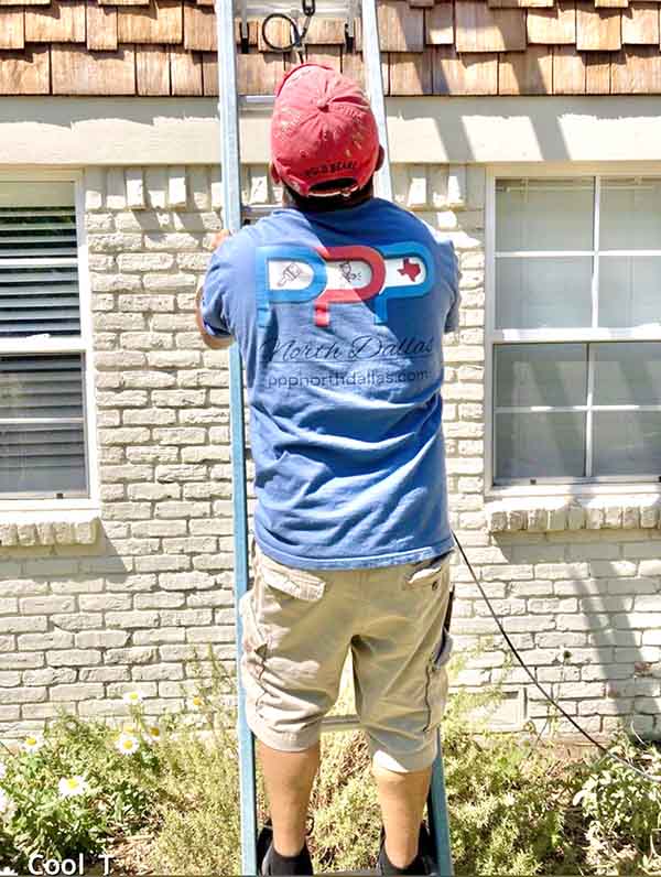 PPP North Dallas painter on ladder working on exterior of white brick home