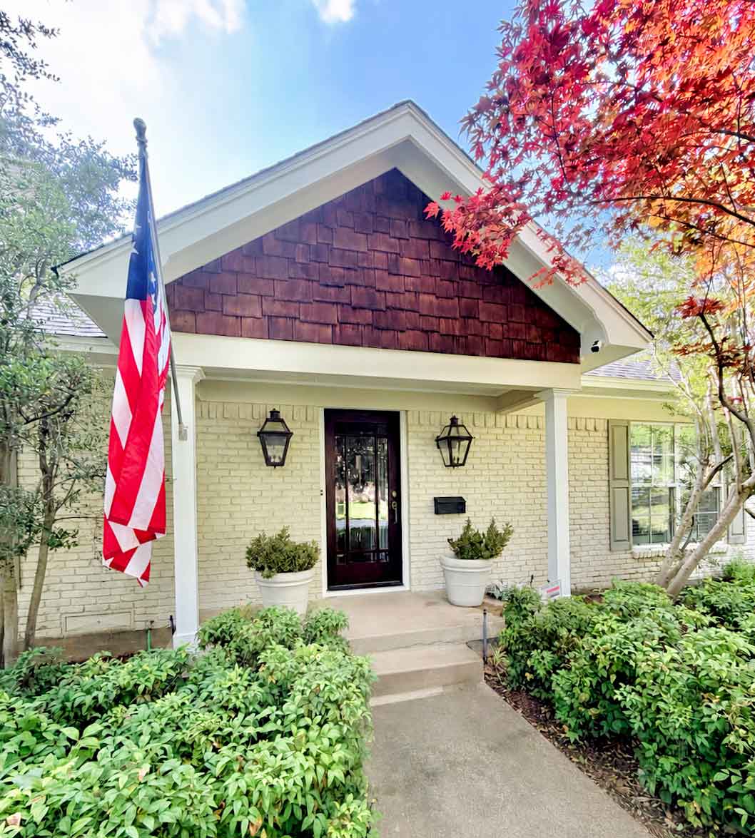 Exterior painted brick home with cream finish, dark front door, and cedar shake gable in North Dallas