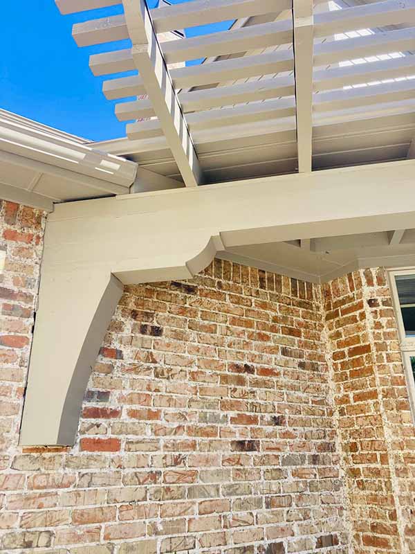 Painted white pergola, soffit, and exterior trim detail on brick home in North Dallas