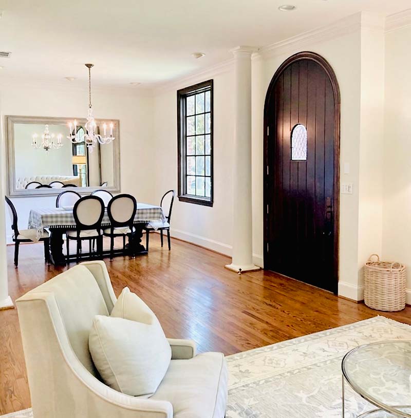 Interior painted living and dining room with cream walls, dark arched door, and crown molding in North Dallas home